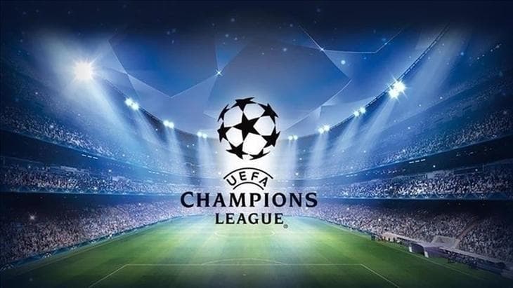 Şampiyonlar Ligi temalı ışıklandırılmış futbol stadyumu ve yeşil saha.