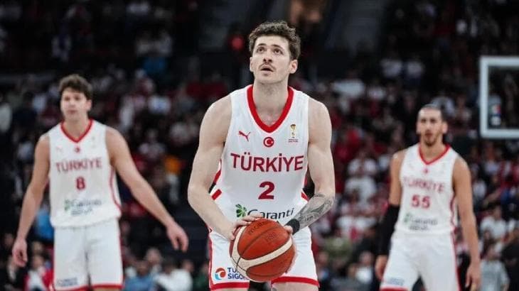 Basketbol sahasında maç öncesi ısınan A Milli Erkek Basketbol Takımı oyuncuları ve salon tribünleri.