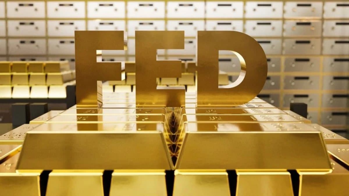 Altın külçeleri ve arka planda finans piyasası verilerini gösteren ekran.