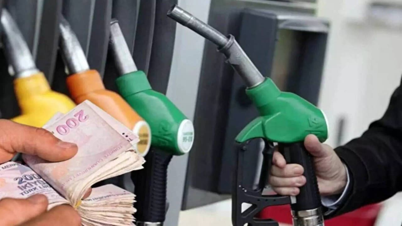 Bir akaryakıt istasyonunda fiyat tabelası ve yakıt almak için bekleyen araçlar.